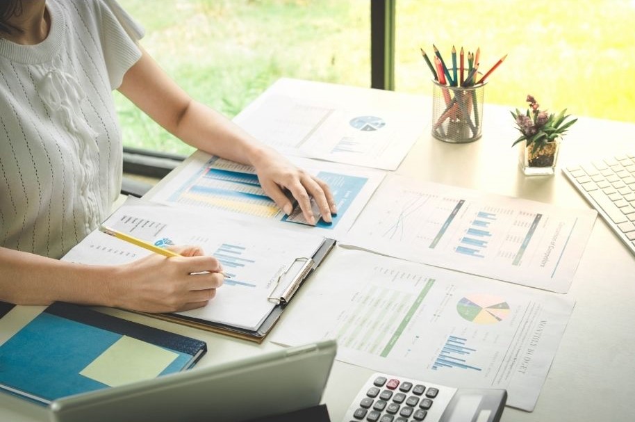 woman at desk with papers showing charts and graphs